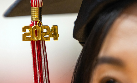 Closeup of a graduate's face showing a 2024 tassel attached to a mortarboard.