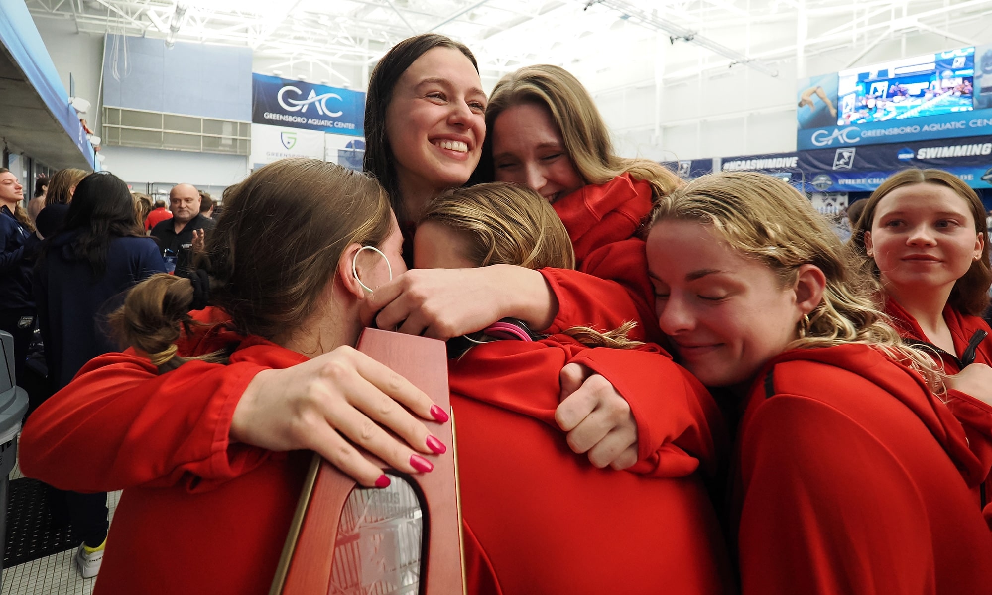 ز,Ȳַ
######### swimmers embrace senior co-captain Tara Culibrk clutching a trophy.