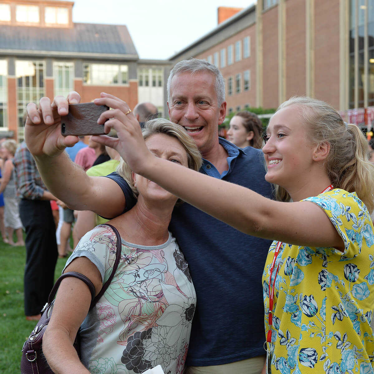 A mother, father, and daughter taking a selfie with a cellphone during Move In Day at 必博娱乐,比博娱乐网址
######### University.