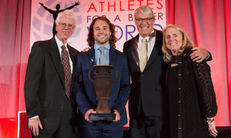 Luke Romick 16 posing on stage with three presenters of his Wooden Cup Award
